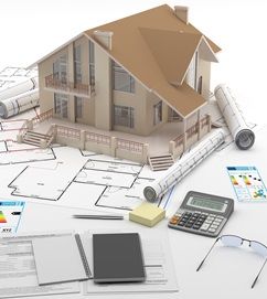 Modellhaus, das auf architektonischen Entwürfen und aufgerollten Plänen steht, umgeben von einem Taschenrechner, Dokumenten, Notizblöcken, Haftnotizen, einem Stift und einer Brille, die für die Planung oder den Bau von Immobilien stehen. 