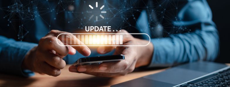 Hände eines Mannes, die ein Handy umfassen. Auf dem Bild ist ein Symbol mit dem Hinweis "Update".